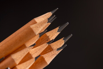 wooden pencils with a black lead on a black background, stacked pencils made of wood and a lead made of graphite
