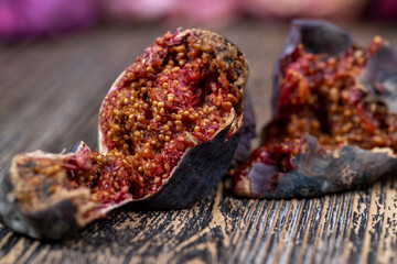 moldy whole overripe and spoiled figs with red flesh and seeds on a table, moldy spoiled figs with lots of grains and red spoiled flesh on a wooden table