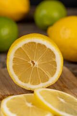 sliced juicy yellow sour lemon lying on the table with limes, sliced ripe citrus fruits lemon and limes are lying on a wooden table