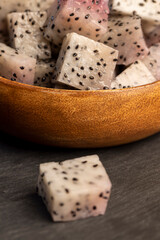 diced ripe pitaya with lots of small black seeds and white soft sweet flesh inside, sweet ripe dragon fruit with black small seeds and light flesh cut in half into small cubes