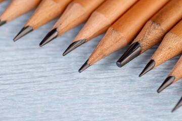 wooden pencils with black lead on blue corrugated paper, several monochrome pencils for sketches or graphic work are in a row.
