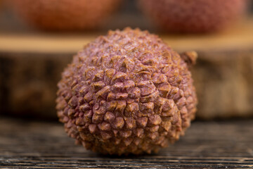ripe lychees scattered on a wooden table, ripe red-skinned lychee fruits,rough textured lychee peel closeup