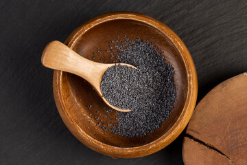 poppy poured into a wooden bowl used in the manufacture of confectionery, a large amount of poppy seeds in a wooden bowl with a spoon
