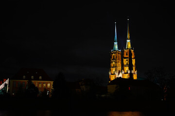 Fototapeta premium View of illuminated Wroclaw Cathedral and Church of the Holy Cross reflected in the Odra River at night. Concept of architecture, travel and religion