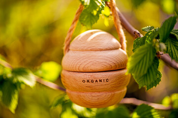 A wooden object with the word organic written on it is hanging from a hazelnut tree branch