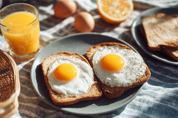 Classic breakfast plate with two sunny-side-up eggs on toast, served with orange juice and fresh eggs in natural light for bright morning food imagery.