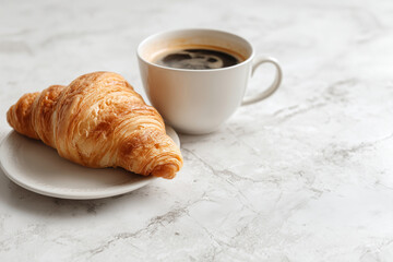 Fresh croissant served on a plate beside a cup of black coffee on a marble surface, captured in bright natural light for clean, minimal breakfast imagery.