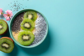 Smoothie bowl with kiwi slices, chia seeds, and yellow puree set on a bright turquoise background, captured in vivid light for eye-catching food visuals.
