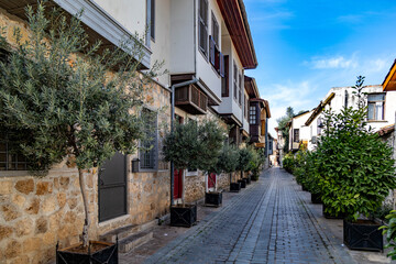A charming stone-paved street in Antalya's historic Kaleiçi district with traditional Ottoman houses featuring cumba bay windows and wooden shutters. Antalya, Turkey.


