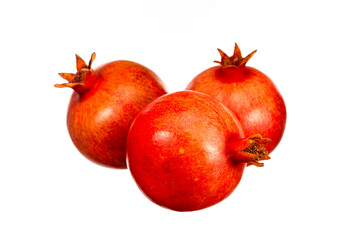 Three red pomegranates are sitting on a white background