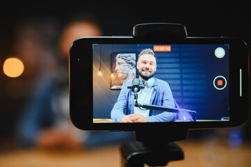 Content creator recording video blog with smartphone and microphone