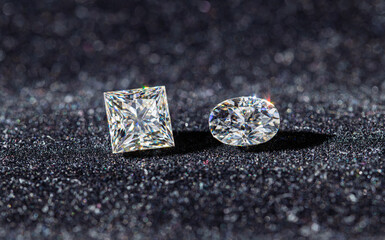 Two diamond shaped gems are on a black surface