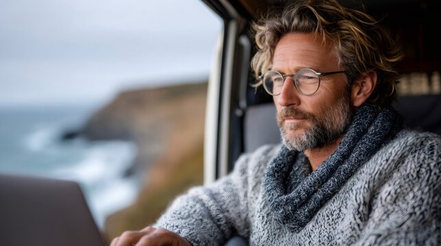 Man working remotely in van by ocean coast