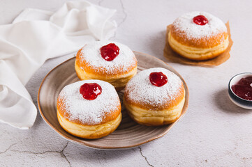 Delicious jam filled donuts with powdered sugar on a plate on the table