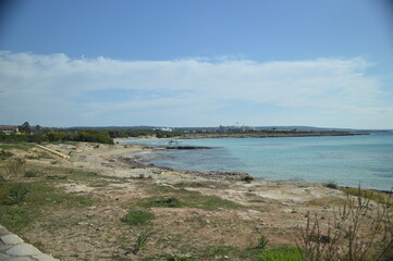Scenic coastal view with rocky shore and clear blue water under a bright sky, tranquil nature landscape, copy space