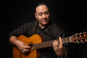 Obraz premium Portrait of a young Brazilian gentleman with a guitar, portrait of a middle-aged man from Brazil, black background, selective focus.