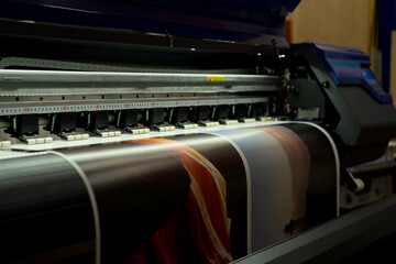 Large format inkjet printer printing colorful graphic on vinyl material in commercial print shop