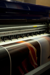 Large format inkjet printer printing colorful graphic on vinyl material in commercial print shop