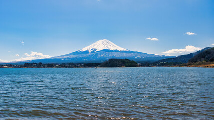 Lake Kawaguchiko, Japan - March 14 2025: Tourists enjoying the view of Lake Kawaguchiko with Mount Fuji in the background. Famous scenery of Mount Fuji in Japan. Blue skies on a cold sunny morning.