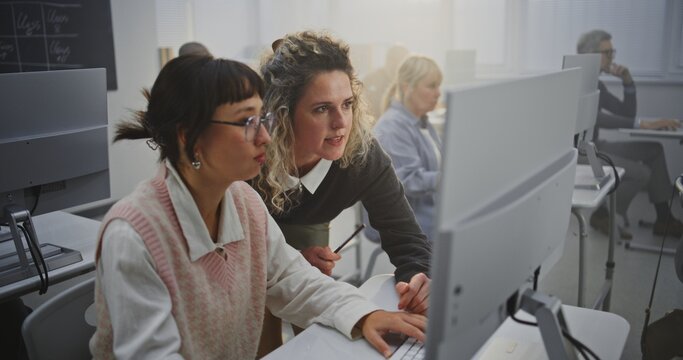 Confident Middle Aged Woman Instructor Supports Adult Female Learner in Computer Lab, Discussing Programming Assignments and Giving Feedback. Concept Lifelong Learning, Digital Literacy, Mentorship.