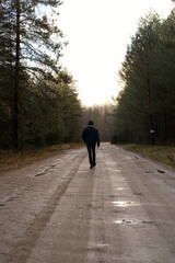 Man Walking Alone on a Dirt Road Through the Forest
