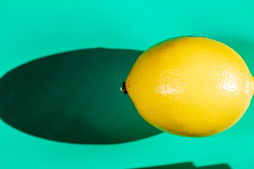 A vibrant yellow lemon resting on a table, captured in soft natural light. The image highlights the fruit&rsquo;s bright color, fresh texture, and simple composition, making it suitable for food photography