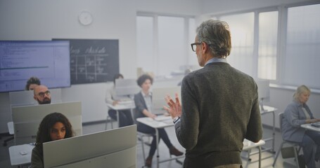Stylish Mature Man Instructor Conducts IT Lecture, Encouraging Adult Students to Engage in...