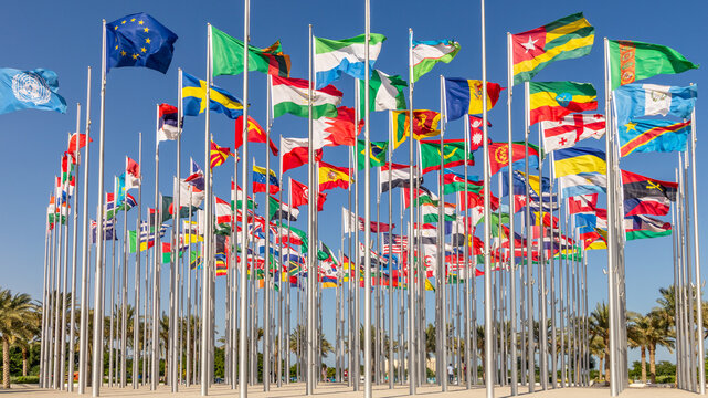 Many world's countries national flags waving on the wind, with United Nations, European Union, Bahrain, Ethiopia, Zambia, Sweden, Congo, Georgia banners in the foreground, Doha, Qatar
