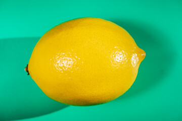 A vibrant yellow lemon resting on a table, captured in soft natural light. The image highlights the fruit&rsquo;s bright color, fresh texture, and simple composition, making it suitable for food photography