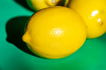 A bright yellow lemon placed on a clean table surface, captured in natural light. The simple composition highlights the vibrant color and fresh texture of the lemon, making it ideal for food photograp