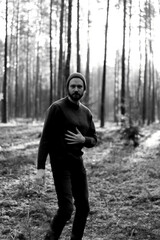 Man walking in a forest at sunset, with sunlight filtering through the trees