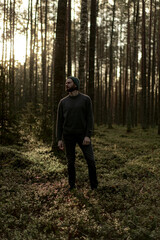 Man walking in a forest at sunset, with sunlight filtering through the trees