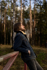 Man Enjoying the Outdoors, Leaning on Fence in Forest