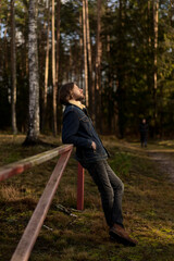Man Enjoying the Outdoors, Leaning on Fence in Forest