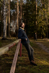 Man Enjoying the Outdoors, Leaning on Fence in Forest