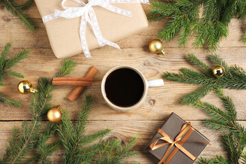 Aromatic coffee in cup, gift boxes, baubles and fir tree branches on wooden table, flat lay....