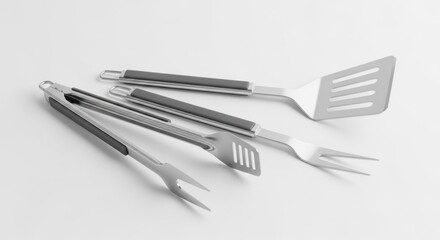 Fototapeta premium Stainless steel barbecue utensils on white, including tongs, spatula, fork, and slotted turner