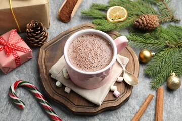 Tasty cocoa, marshmallows, cinnamon, candy cane and Christmas decor on grey table, closeup