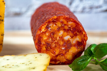 Thin slices of kulen arranged neatly on a plate, showcasing the rich red color and distinctive marbled texture of this traditional cured sausage. Soft natural lighting enhances the savory details and 