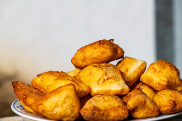 Golden, freshly fried fritters arranged on a plate, featuring a crispy exterior and a soft, airy inside. Warm lighting enhances their rich golden color and homemade rustic appearance. 