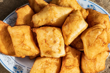 Golden, freshly fried fritters arranged on a plate, featuring a crispy exterior and a soft, airy inside. Warm lighting enhances their rich golden color and homemade rustic appearance.