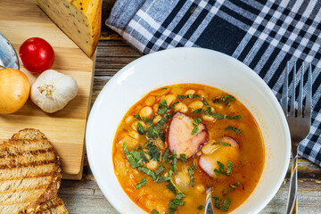 A hearty bowl of cooked bean stew with tender pieces of meat, served in a clean white dish. The warm, rich broth highlights the soft beans and juicy meat, while natural lighting 
