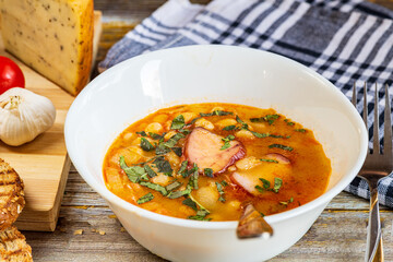 A hearty bowl of cooked bean stew with tender pieces of meat, served in a clean white dish. The warm, rich broth highlights the soft beans and juicy meat, while natural lighting 