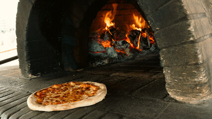 Wood-fired oven with glowing coal and beautiful flames, featuring a fresh Margherita pizza at the oven mouth. Authentic Italian cooking, rustic and inviting.