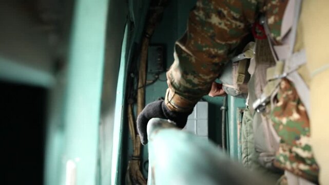 Military paratrooper checks altimeter gauge inside a cargo aircraft before performing a static line parachute jump for airborne operations.