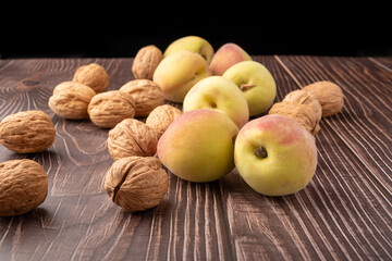 Walnuts and peaches, walnuts in their shells and peaches arranged on a rustic table, Selective Focus.
