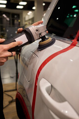 Polishing black car surface thoroughly, Detailed buffing to achieve showroom quality shine, Expert technician uses orbital buffer and foam pad to enhance vehicle gloss