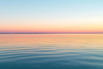 Fototapeta premium Evening sky glows with warm hues during sunset over calm water surface
