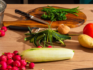 Fresh vegetables, peeled zucchini, chives, radishes and an egg on a kitchen countertop. Natural cooking preparation scene.