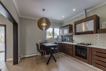 Cozy kitchen interior in a private house. Kitchen set with a dark wood facade.
